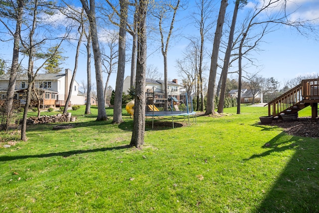 view of yard featuring stairway, a residential view, a wooden deck, and a trampoline