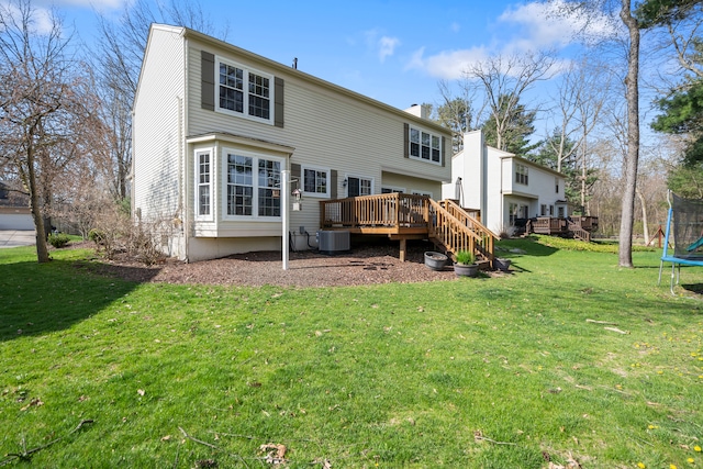 rear view of property featuring central AC, a trampoline, a wooden deck, and a yard