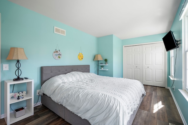 bedroom with baseboards, a closet, dark wood-style floors, and visible vents