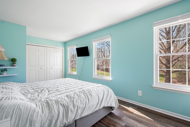 bedroom featuring visible vents, baseboards, dark wood-style floors, and a closet