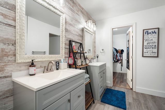 full bathroom featuring two vanities, a sink, and wood finished floors