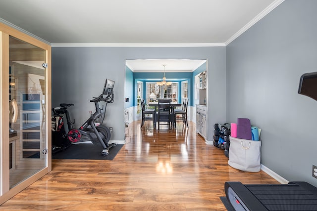 exercise area with crown molding, baseboards, a notable chandelier, and wood finished floors