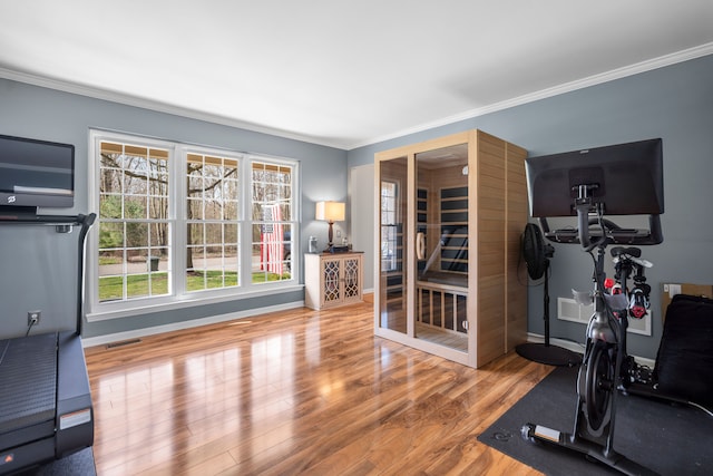 workout room featuring crown molding, baseboards, visible vents, and wood finished floors