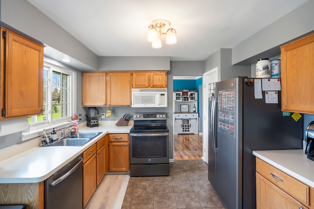 kitchen with brown cabinets, a sink, light countertops, tile patterned floors, and stainless steel appliances