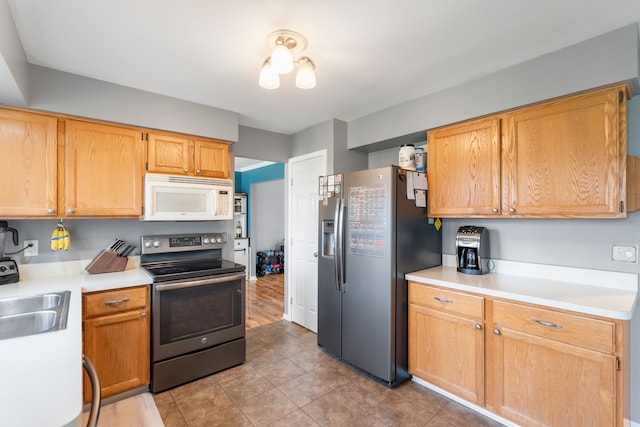 kitchen with light countertops, light tile patterned floors, appliances with stainless steel finishes, and a sink