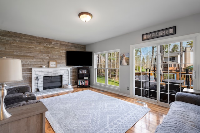 living area featuring a fireplace, wood walls, wood finished floors, and visible vents
