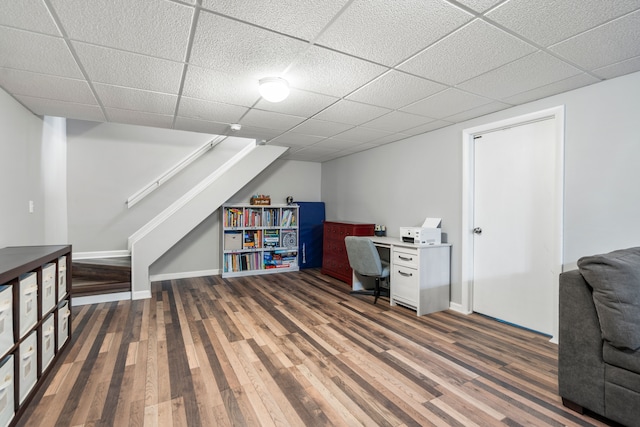 home office with baseboards, a drop ceiling, and wood finished floors
