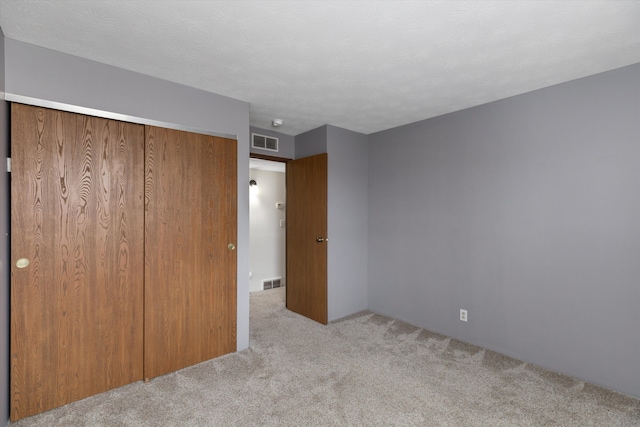 unfurnished bedroom featuring carpet flooring, visible vents, and a closet