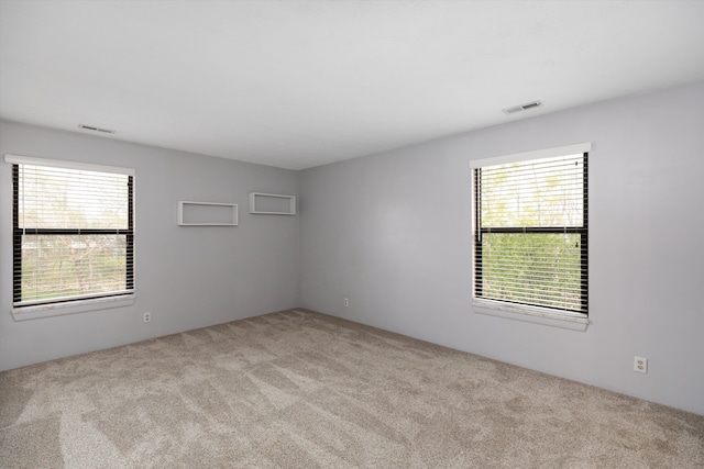spare room featuring carpet flooring, visible vents, and plenty of natural light