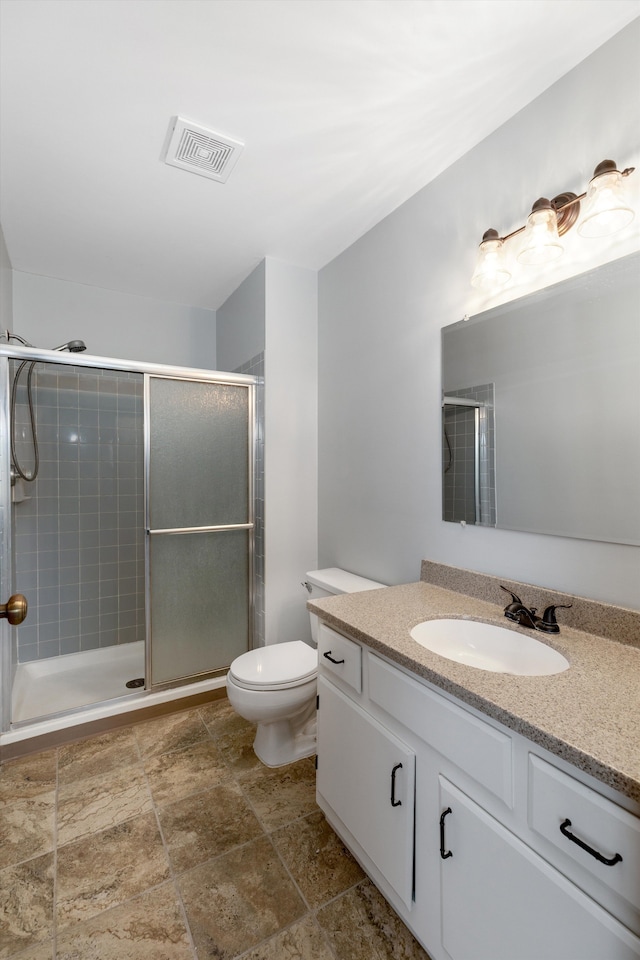 full bath featuring vanity, a stall shower, toilet, and visible vents
