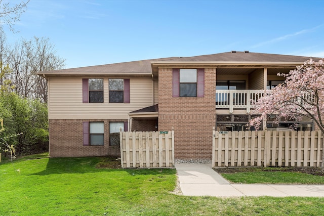 view of front facade with brick siding, fence, and a front lawn