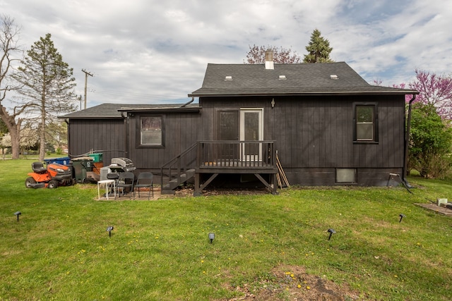 back of house with a lawn, a wooden deck, and a shingled roof
