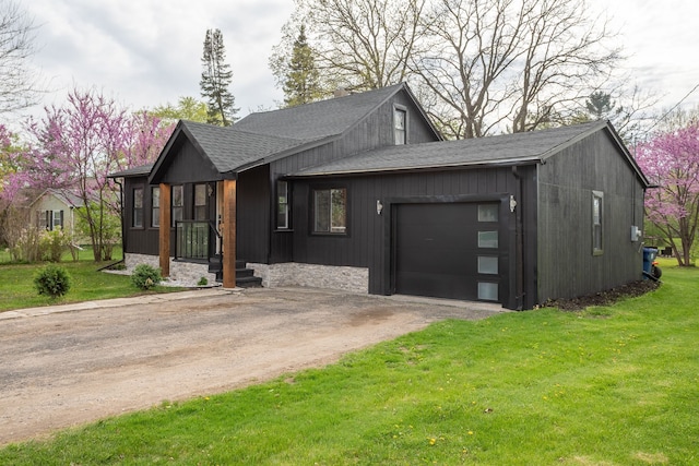 view of front of property featuring roof with shingles, an attached garage, driveway, and a front yard