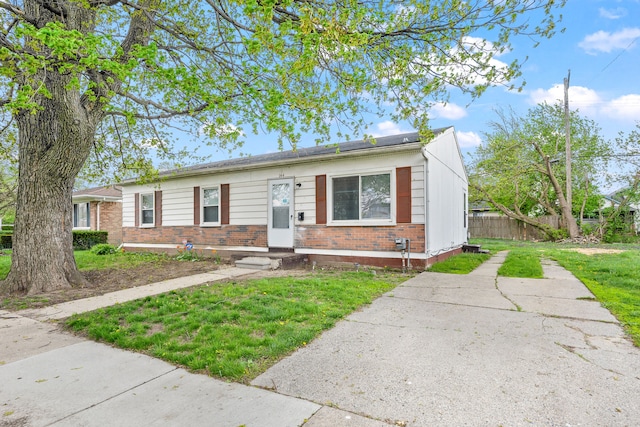 view of front of property with brick siding, fence, and a front yard