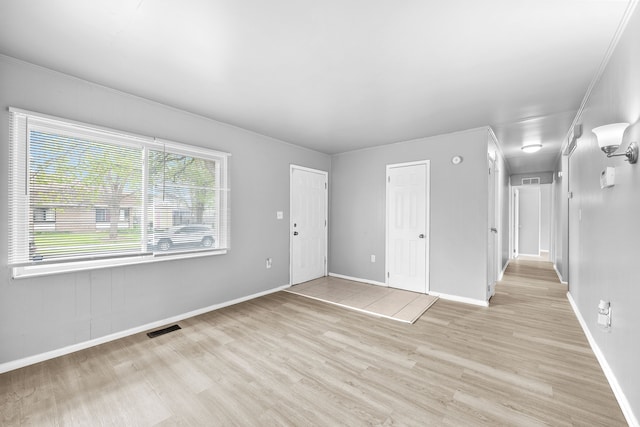 interior space featuring light wood-style floors, baseboards, and visible vents