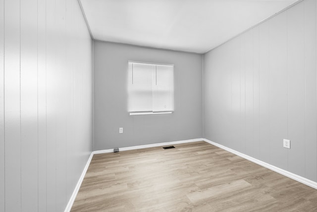 empty room featuring baseboards, visible vents, and wood finished floors