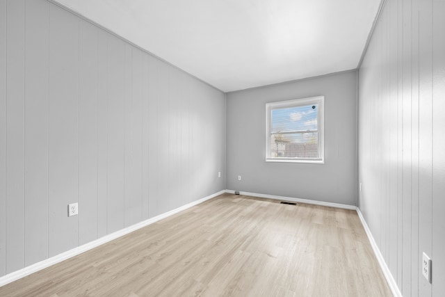 spare room with baseboards, visible vents, and light wood-type flooring