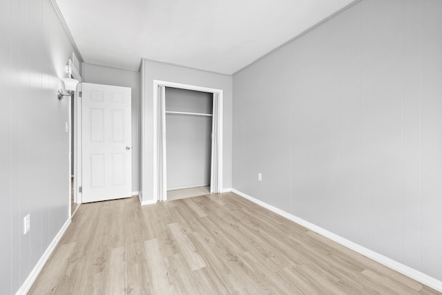 unfurnished bedroom featuring baseboards, light wood finished floors, and a closet