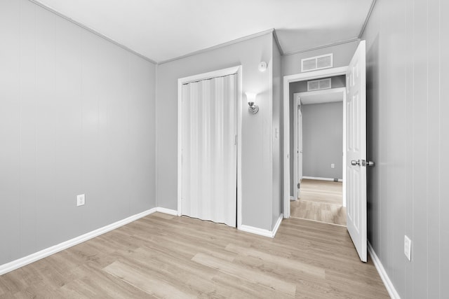 unfurnished bedroom featuring visible vents, light wood-style flooring, baseboards, and a closet