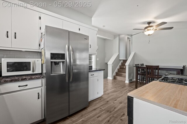 1128 Braeview Dr, Howell, MI 48843 - kitchen featuring stainless steel fridge with ice dispenser, white microwave, a ceiling fan, decorative backsplash, and white cabinets