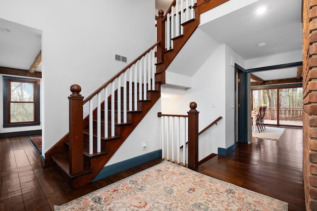 staircase featuring visible vents, baseboards, beam ceiling, and hardwood / wood-style flooring
