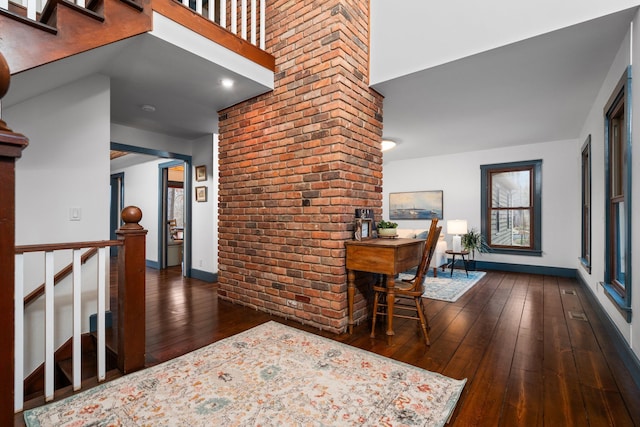 interior space with baseboards, brick wall, and hardwood / wood-style floors