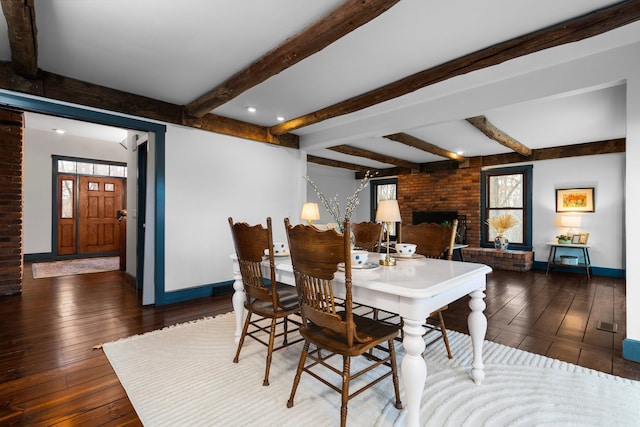 dining area with wood-type flooring, baseboards, and a brick fireplace