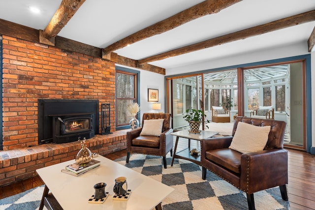 living area featuring wood-type flooring, beam ceiling, and a fireplace