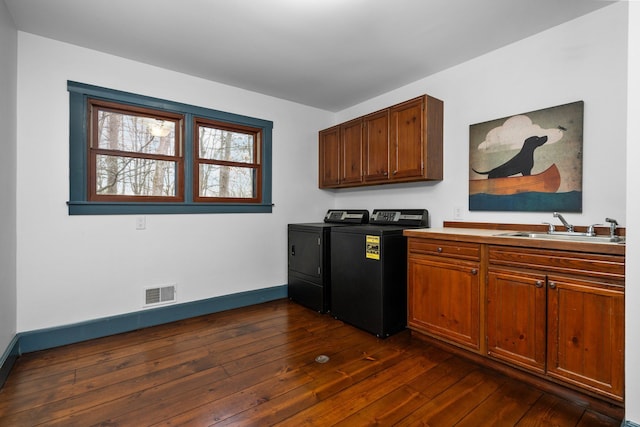 laundry area with dark wood-style flooring, visible vents, cabinet space, a sink, and separate washer and dryer