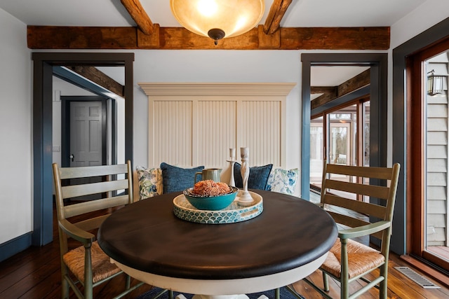 dining area with a healthy amount of sunlight, beamed ceiling, hardwood / wood-style flooring, and visible vents