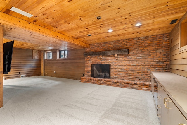 unfurnished living room with wooden walls, wood ceiling, carpet, and a fireplace