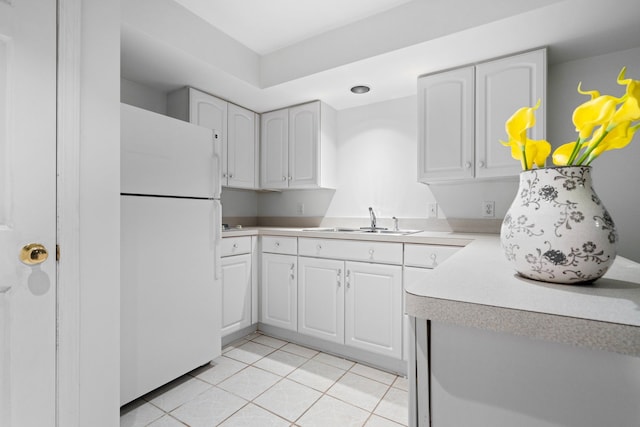 kitchen with freestanding refrigerator, light tile patterned floors, white cabinets, and a sink