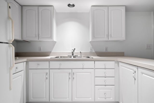 kitchen with a sink, light countertops, white cabinets, and freestanding refrigerator