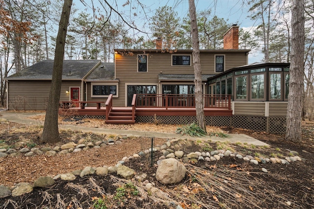back of property featuring a sunroom, a wooden deck, and a chimney