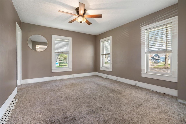 carpeted empty room with baseboards, a ceiling fan, and a healthy amount of sunlight