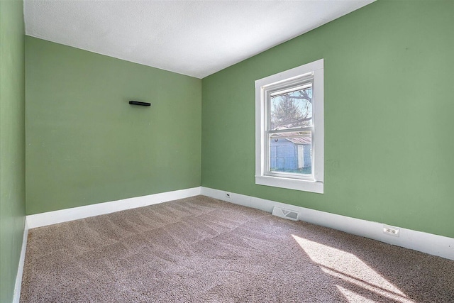 carpeted empty room featuring visible vents and baseboards