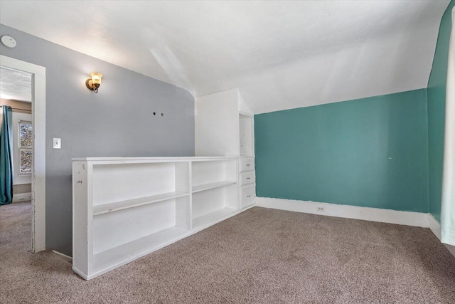 interior space with carpet floors, baseboards, and vaulted ceiling