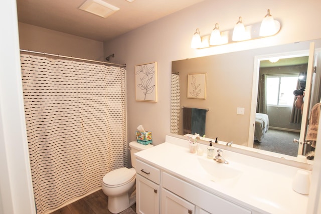 ensuite bathroom featuring connected bathroom, toilet, wood finished floors, and vanity