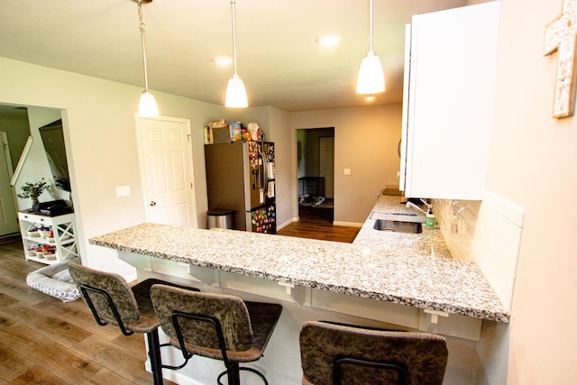 kitchen featuring stainless steel fridge with ice dispenser, dark wood-style flooring, and light stone counters