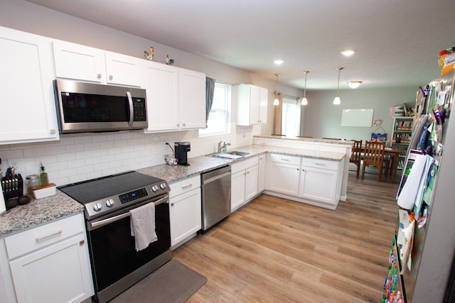 kitchen featuring a sink, stainless steel appliances, a peninsula, and white cabinetry