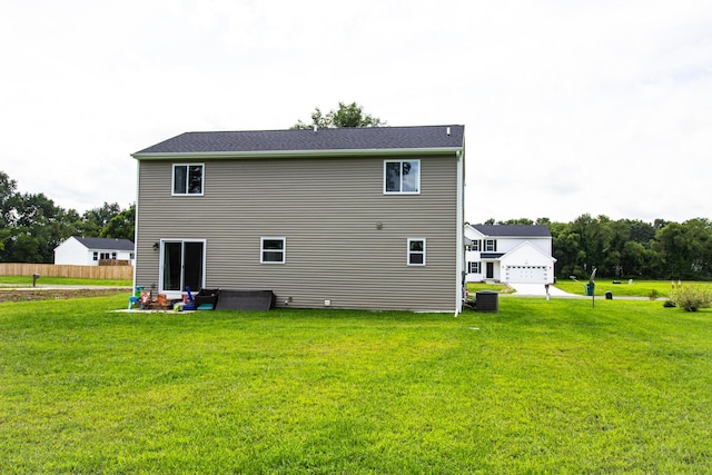 rear view of property featuring a lawn and central AC unit
