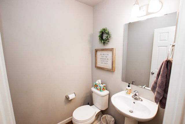 bathroom with toilet, baseboards, and a sink