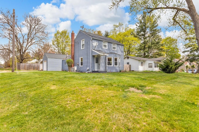 back of house with fence, an outbuilding, a chimney, and a yard