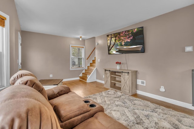 living room with visible vents, stairs, baseboards, and wood finished floors