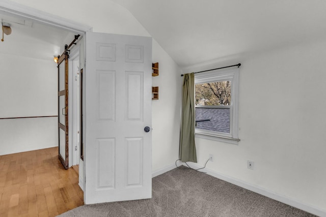interior space featuring baseboards, vaulted ceiling, and a barn door