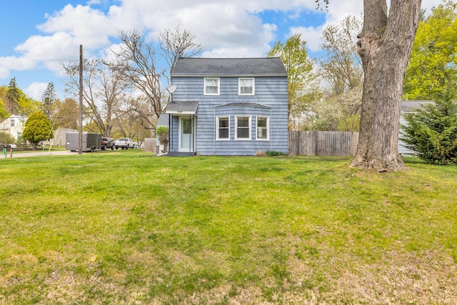 rear view of property with fence and a yard