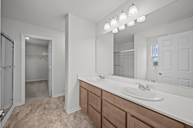 bathroom featuring double vanity, a sink, a stall shower, and a spacious closet