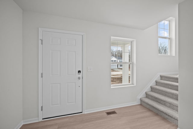 entrance foyer with visible vents, stairs, baseboards, and light wood-type flooring
