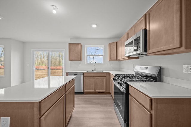 kitchen featuring light countertops, a sink, light wood finished floors, and stainless steel appliances