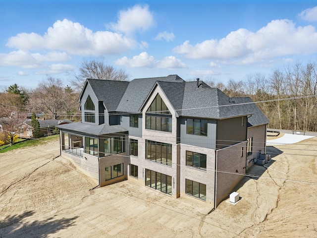 rear view of property featuring roof with shingles and a sunroom